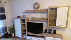 A modern living room with a flat-screen TV, built-in speakers, a wooden entertainment unit, and a glass-fronted cabinet. - Bergspitze (Garmisch-Partenkirchen)