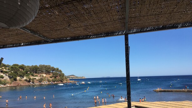 A beachside view with a wooden deck, a clear blue sky, and boats in the water. - Peaceful charming paradise, beach at 70m, private swimming pool,  plancha (La Seyne-sur-Mer)