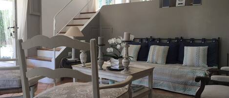 A living room with a staircase, a sofa set, and a dining table with chairs.