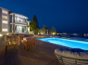 Un espace piscine moderne doté d’une terrasse en bois, de chaises longues et d’une grande piscine.