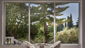 Une chambre moderne avec deux chaises blanches, disposées face à une grande fenêtre donnant sur un jardin luxuriant.