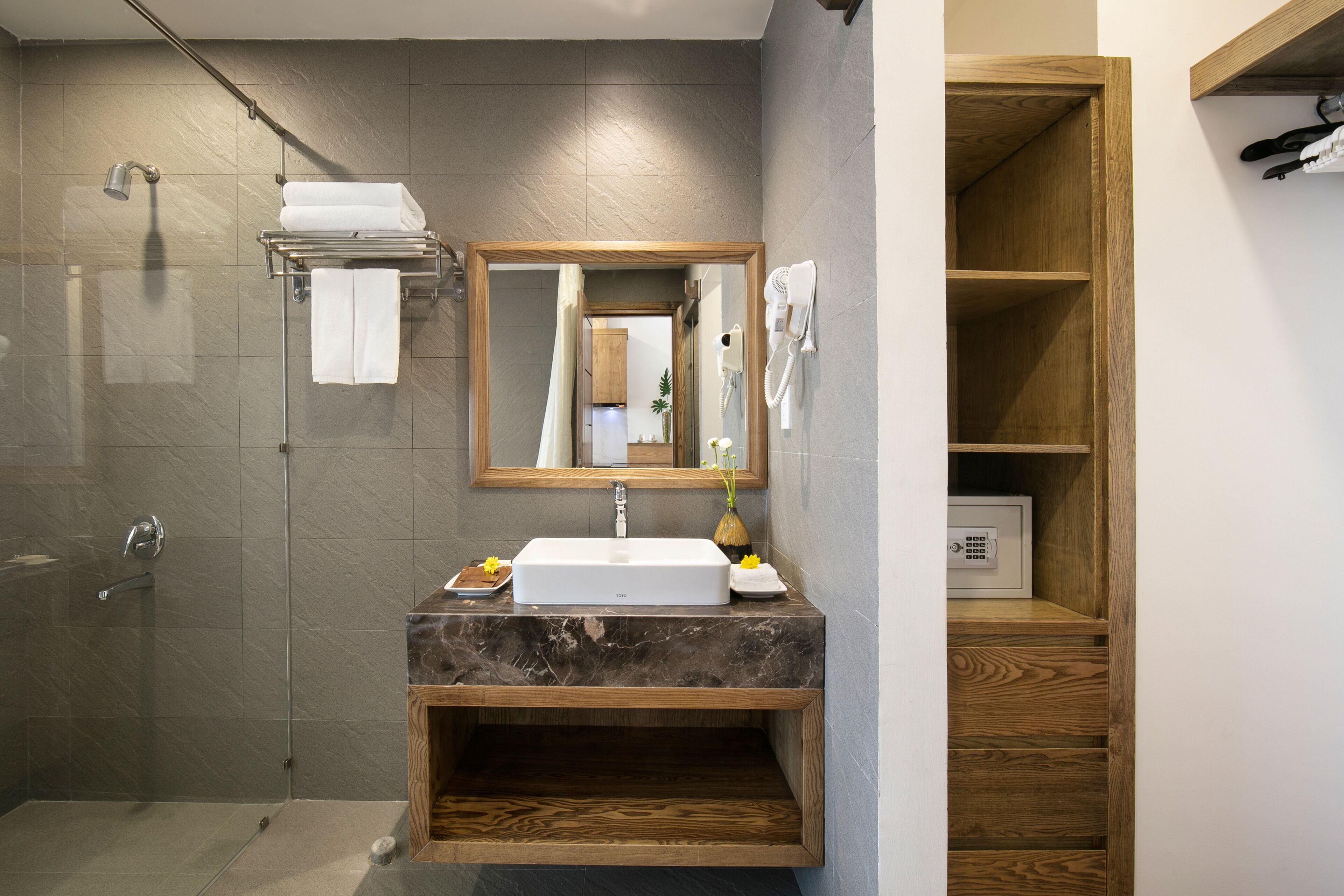 A modern bathroom with a glass-enclosed shower, a marble sink, and a wooden vanity.