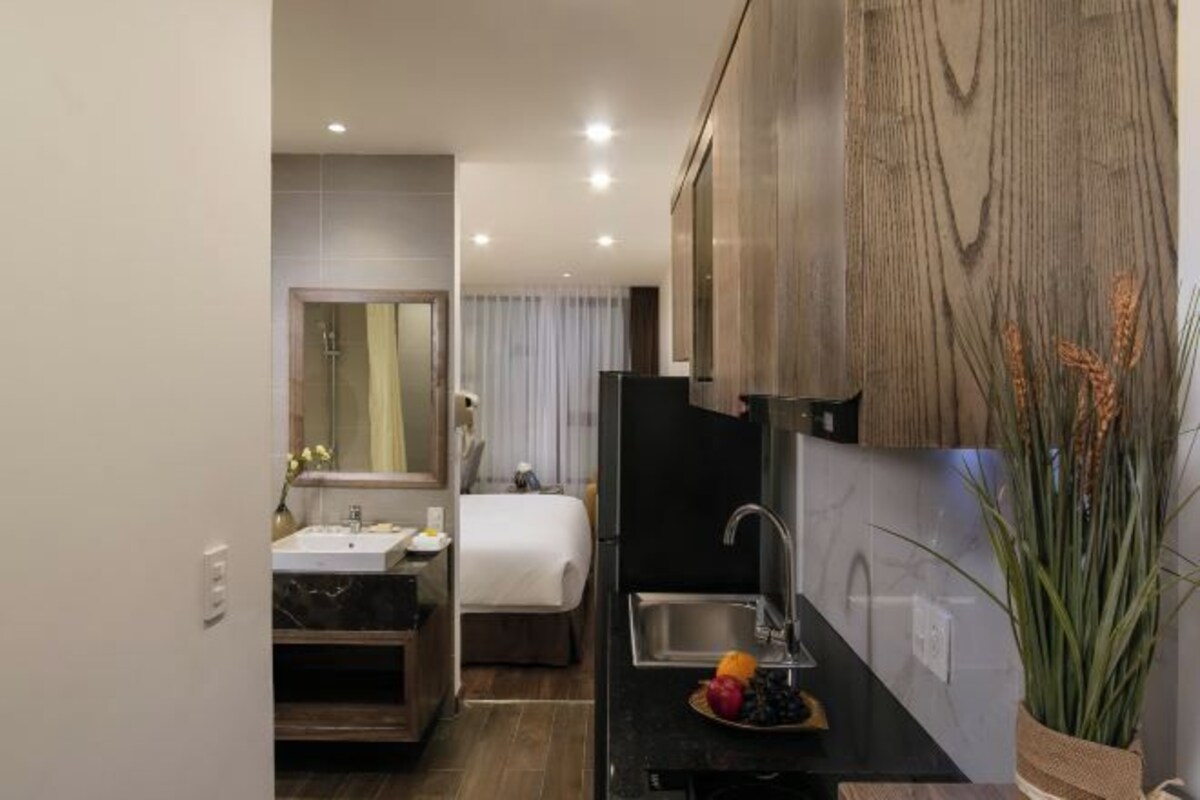 A modern hotel room with a separate bathroom, a small kitchenette, and a bed with a view.