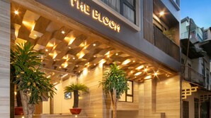 A modern building with a sign reading "The Bloom." It features a wooden ceiling with embedded lights, a staircase leading to the entrance, and potted plants. - The Bloom Pham Viet Chanh - Modern Living Space in Saigon - A Top Choice for Western Travelers (Ho Chi Minh City)