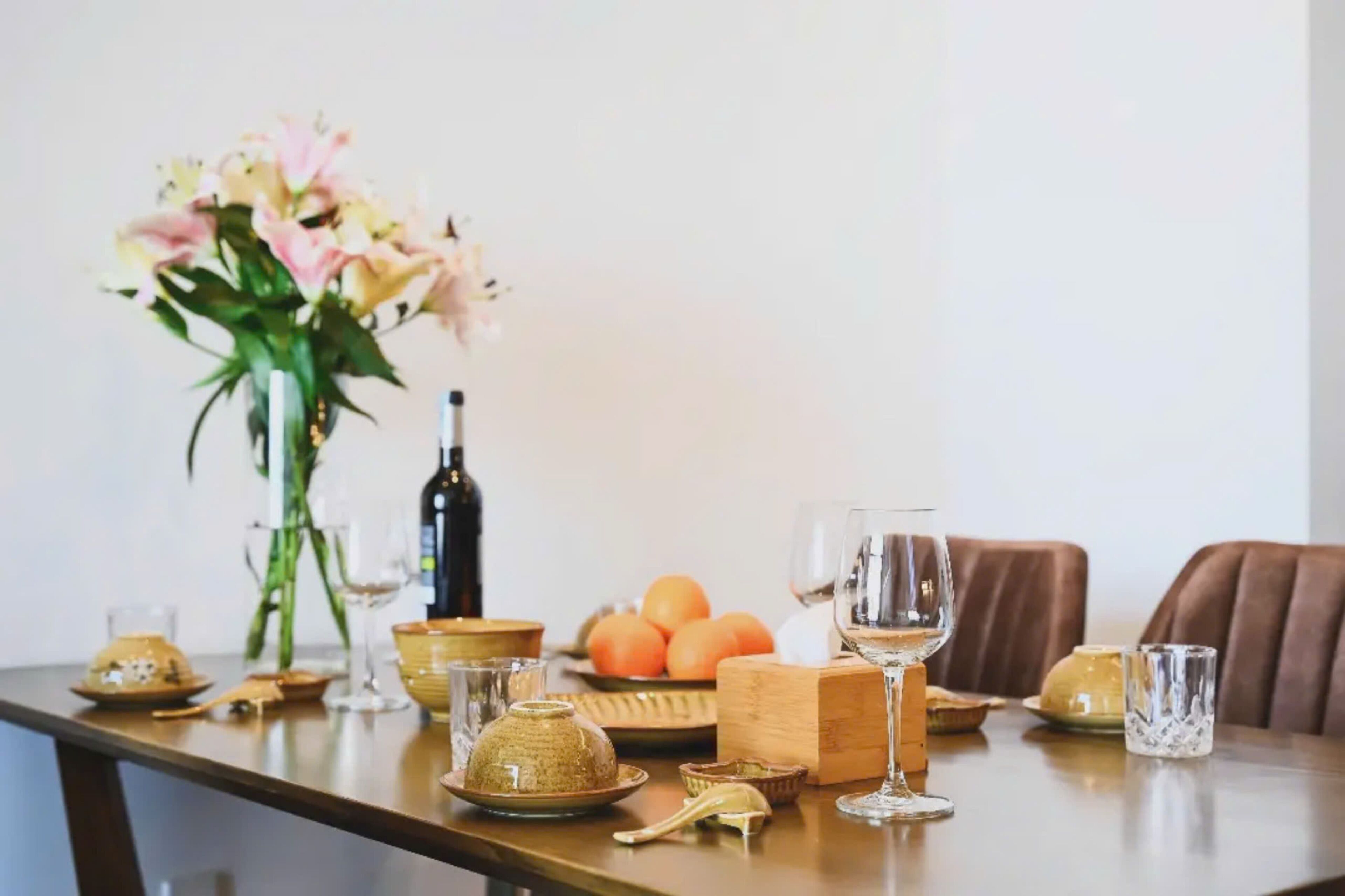 A dining table set with various dishes, a bottle, and a vase of flowers.