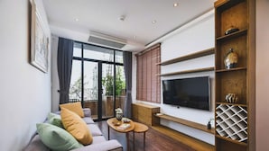A modern living room with a sofa, coffee table, TV, and wooden shelving. - The Bloom Pham Viet Chanh - Modern Living Space in Saigon - A Top Choice for Western Travelers (Ho Chi Minh City)