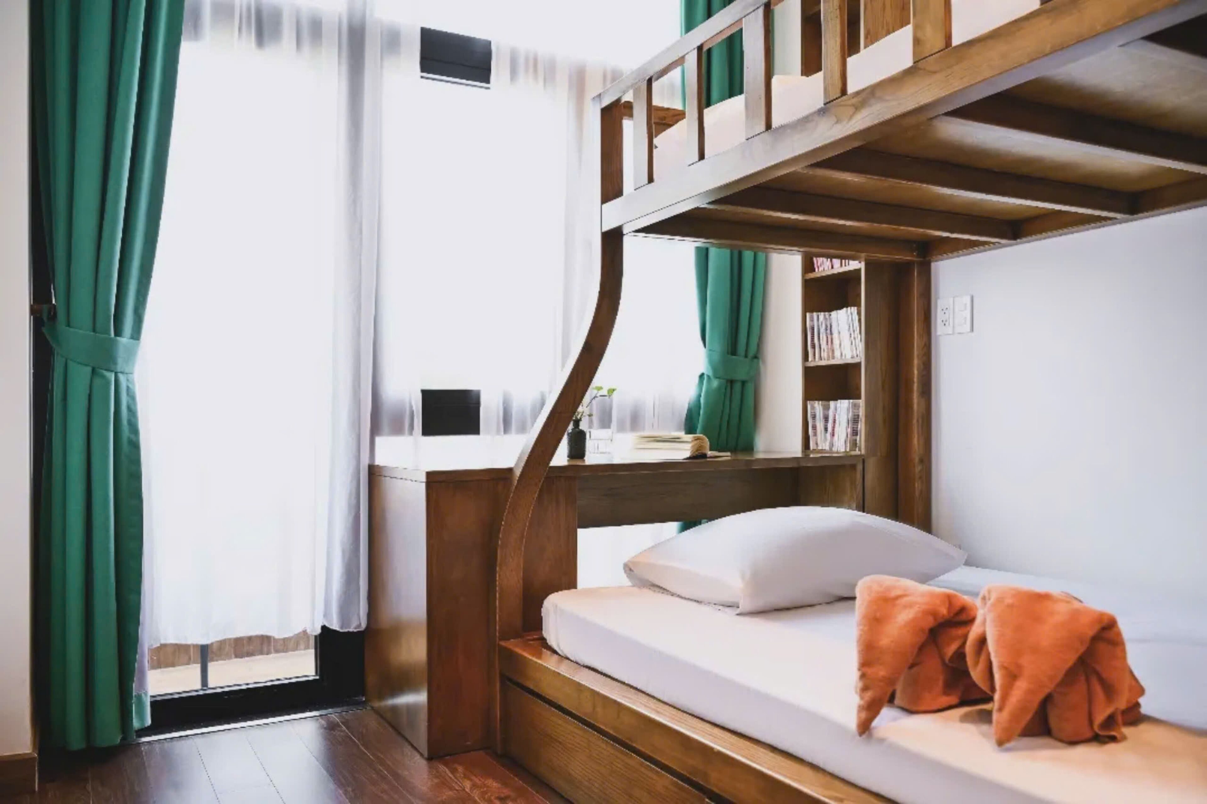 A bunk bed with a wooden frame, a bedside table, and a bookshelf.