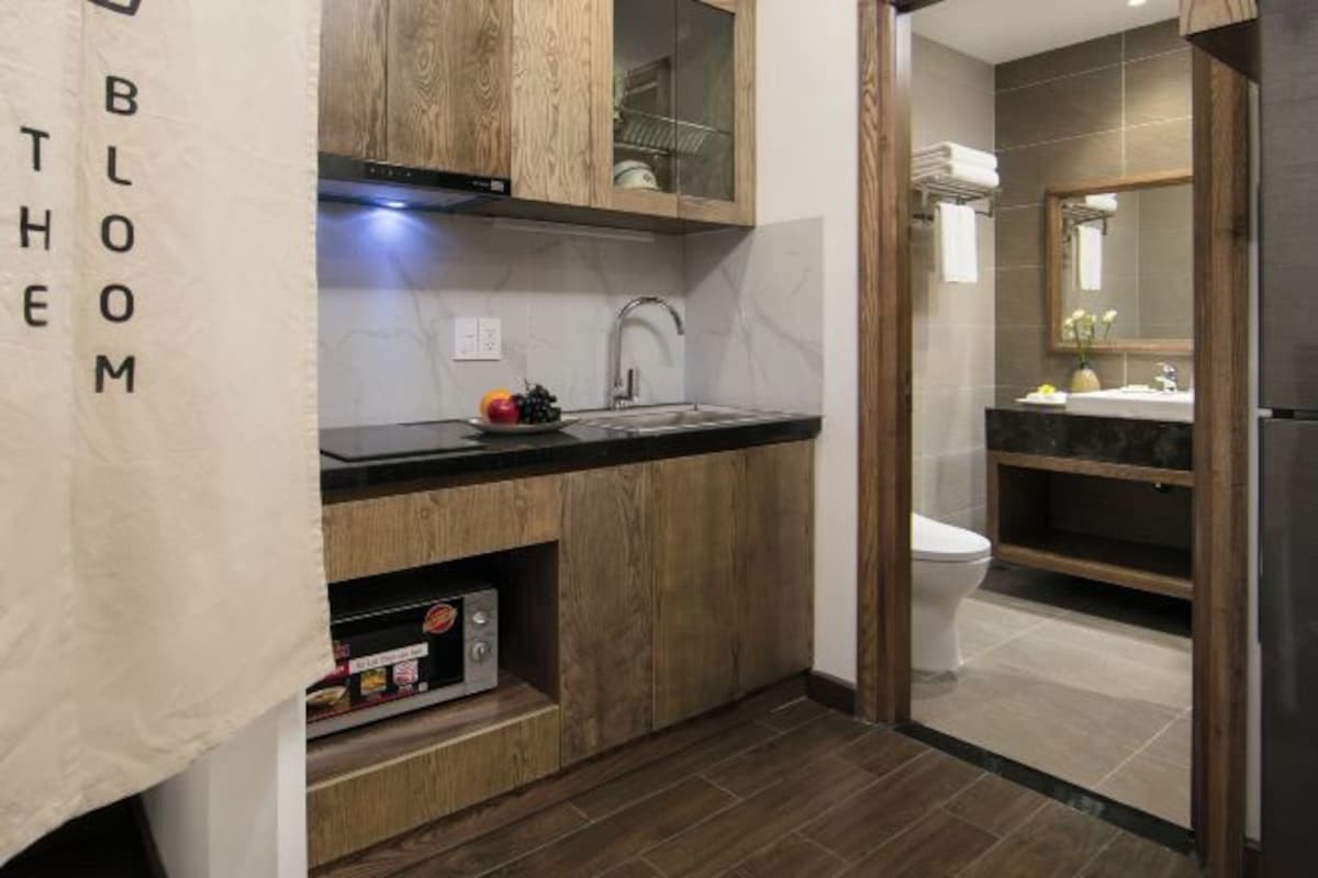 Una cocina moderna con armarios de madera, encimera negra y microondas integrado.