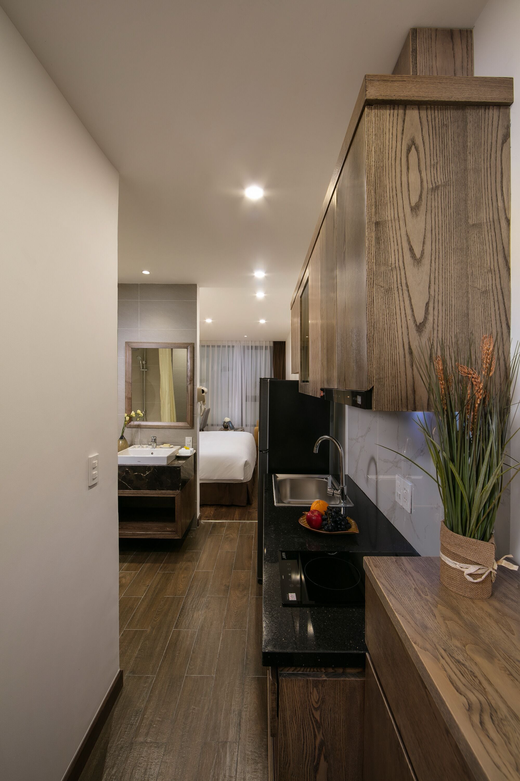 Une chambre d’hôtel moderne équipée d’une kitchenette, d’un lit et d’une salle de bain.