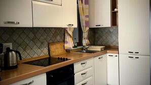 A modern kitchen with white cabinets, a wooden countertop, a built-in oven, and a sink.