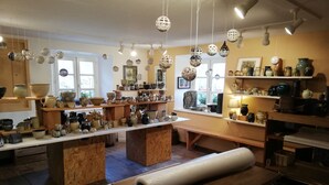 A pottery workshop with shelves of ceramics, a wooden table with a rolled-up mat, and hanging decorative lights. - apartment/ flat - LAPOUTROIEHouse with character (Lapoutroie)