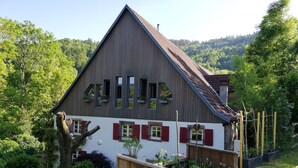 A two-story house with a sloped roof, wooden siding, and red shutters. - apartment/ flat - LAPOUTROIEHouse with character (Lapoutroie)