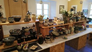 A display of various ceramic items on shelves and tables in a well-lit room with wooden accents and a window in the background. - apartment/ flat - LAPOUTROIEHouse with character (Lapoutroie)