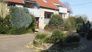 Een woonhuis genaamd "Am Kral" met een gevel van natuursteen, een dak met rode tegels en een aangelegde tuin.