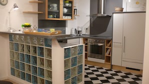 Een keuken met een geruit vloertje, een fornuis, een spoelbak en een kast met glazen deuren.