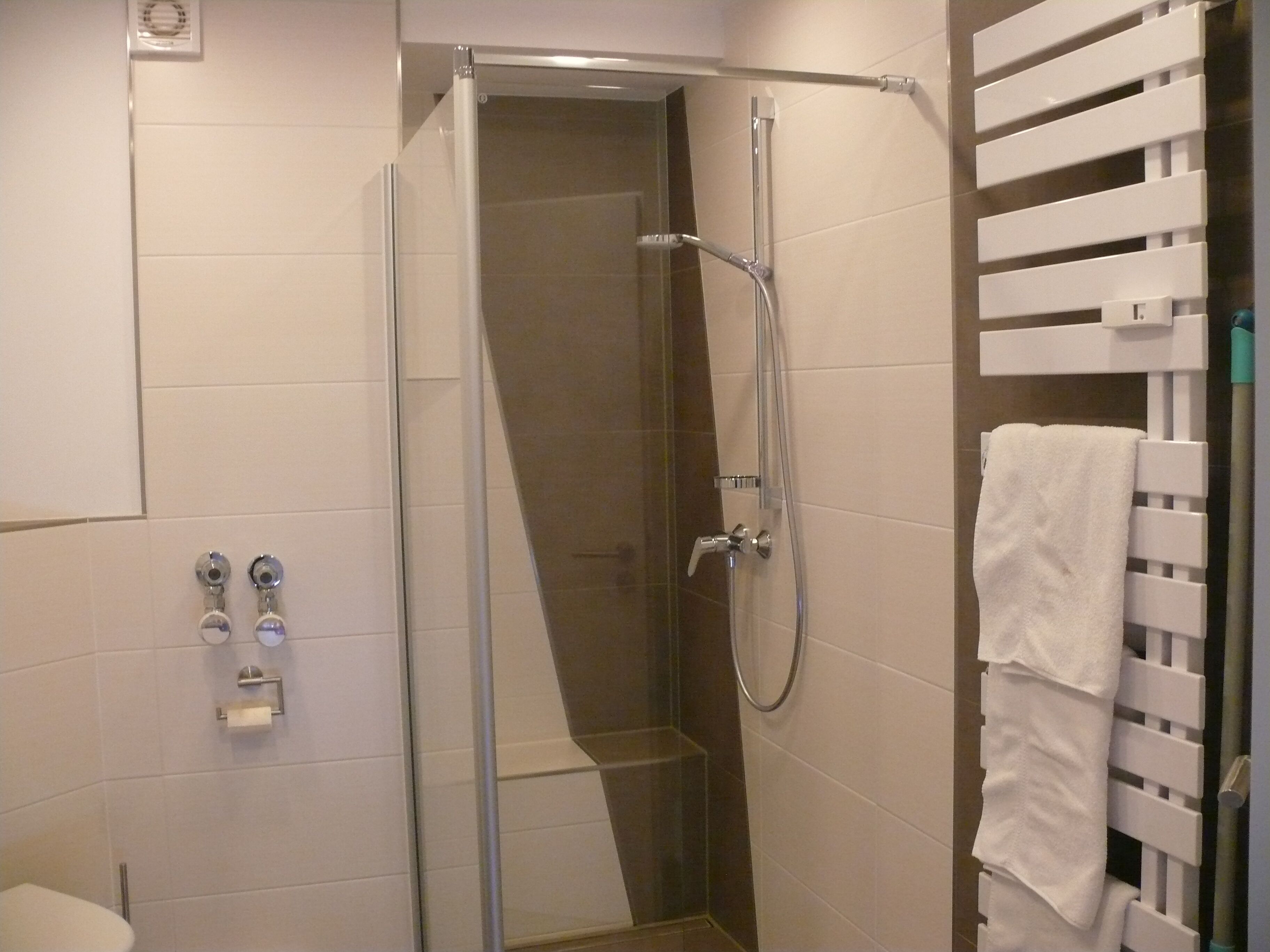 Ein modernes Badezimmer mit einer Duschkabine, einer Toilette und einem Handtuchhalter.