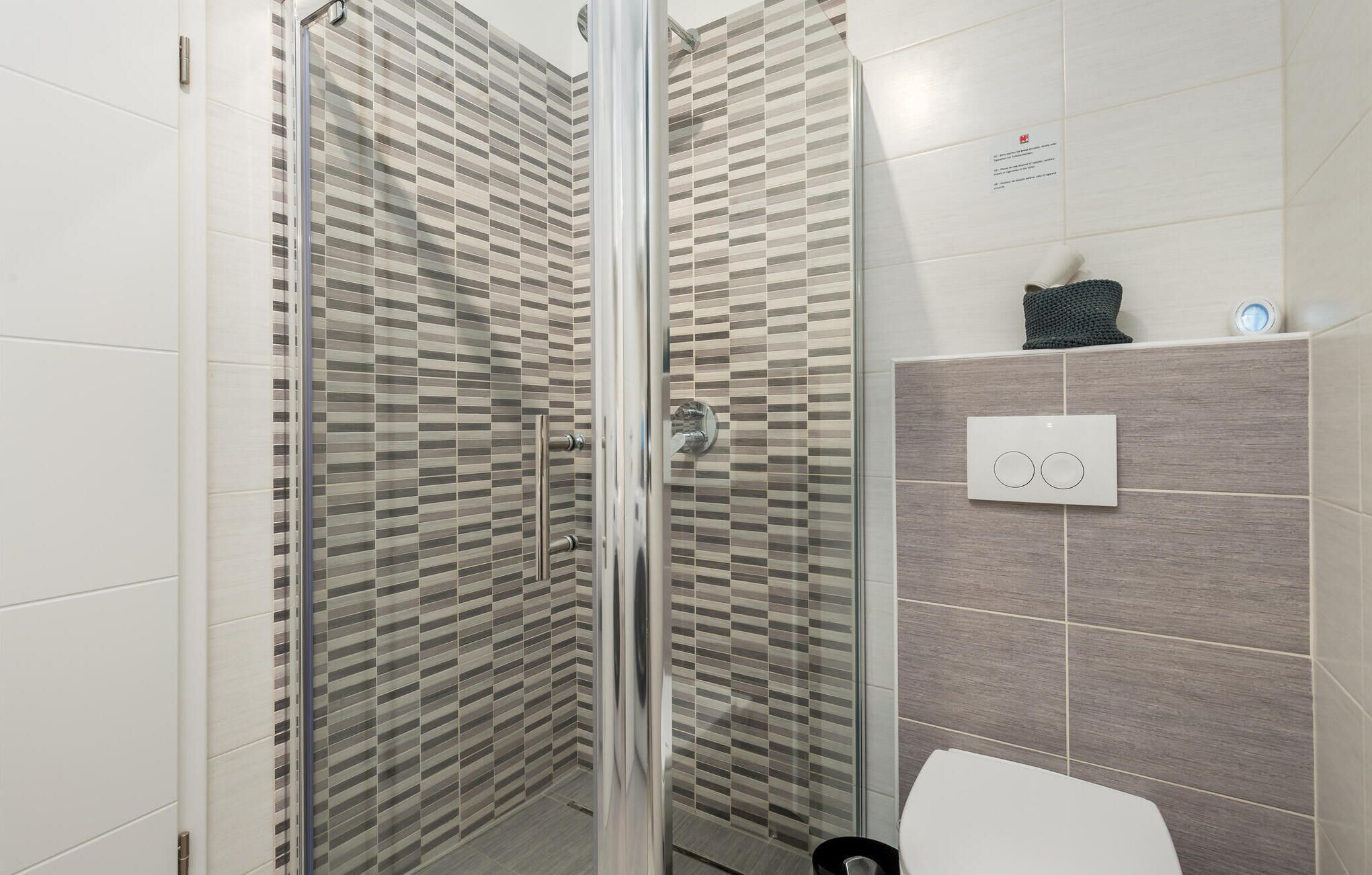 Une salle de bain moderne avec une douche à parois de verre, des toilettes et un porte-serviettes.