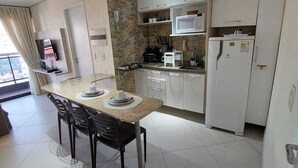 Una cocina moderna con armarios blancos, microondas, refrigerador y un comedor con mesa y sillas.