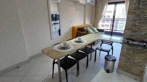 Una cocina moderna con comedor, que incluye una mesa larga con sillas, un cubo de basura pequeño y una estufa empotrada.
