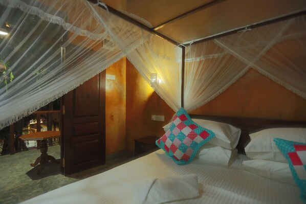 A bedroom with a canopy bed, a wooden door, and a small table.