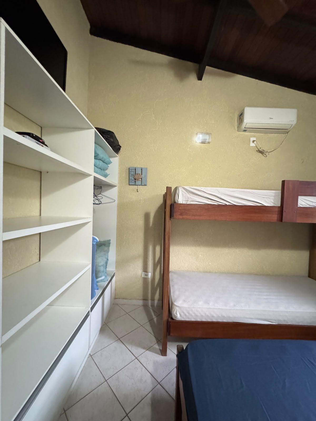 Une chambre avec un lit superposé, une armoire blanche et une étagère.