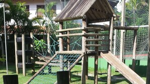 A playground with a wooden climbing structure, a slide, and a rope bridge. - House in gated community beachfront - sleeps 8 - weekends/seasonal rental (São Sebastião)