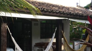 A house with a patio area featuring a hammock, outdoor furniture, and potted plants. - House in gated community beachfront - sleeps 8 - weekends/seasonal rental (São Sebastião)