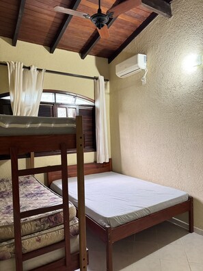Un llit superposat amb una finestra, un ventilador de sostre i un aire condicionat.