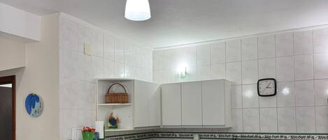 A kitchen with a dining table, chairs, a ceiling fan, a microwave, a sink, and a stove.
