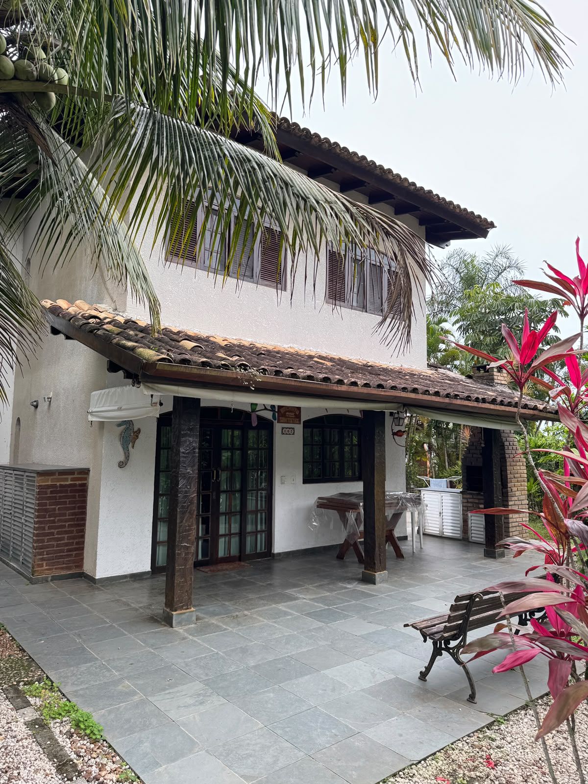 A building with a tiled roof, a covered patio area, and a bench.