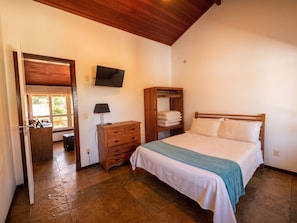 Un dormitorio con cama, escritorio, televisor y armario.