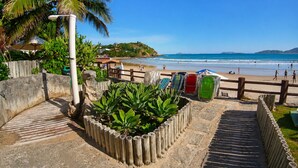 A beach with a wooden fence, a palm tree, and a clear blue sky.