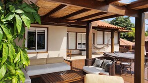 A covered outdoor seating area with a wooden table, a sofa, and a hammock.