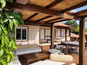 Un espacio de estar al aire libre cubierto con una mesa de madera, un sofá y una hamaca.