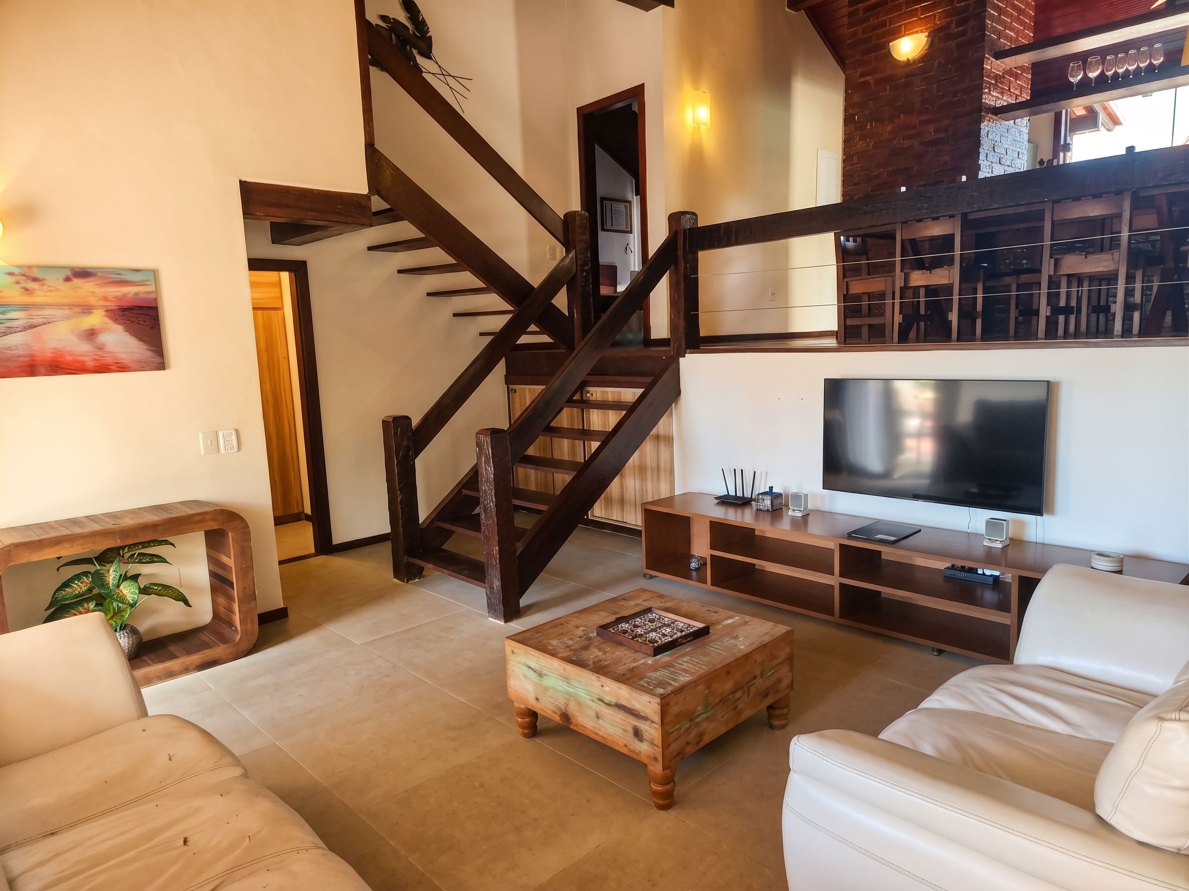 A living room with a wooden staircase, a flat-screen TV, a coffee table, and a sofa.