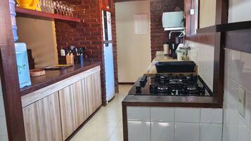 A kitchen with a brick wall, a gas stove, and a refrigerator.
