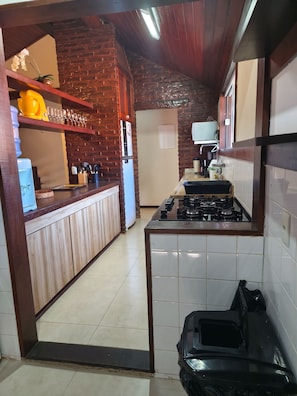 Una cocina con pared de ladrillo, estufa a gas y refrigerador.