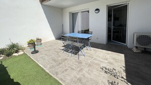 A patio with a blue table and chairs, a small garden, and a sliding glass door leading to an interior space. - Mini villa the top of bonifacio with heated pool (Bonifacio)