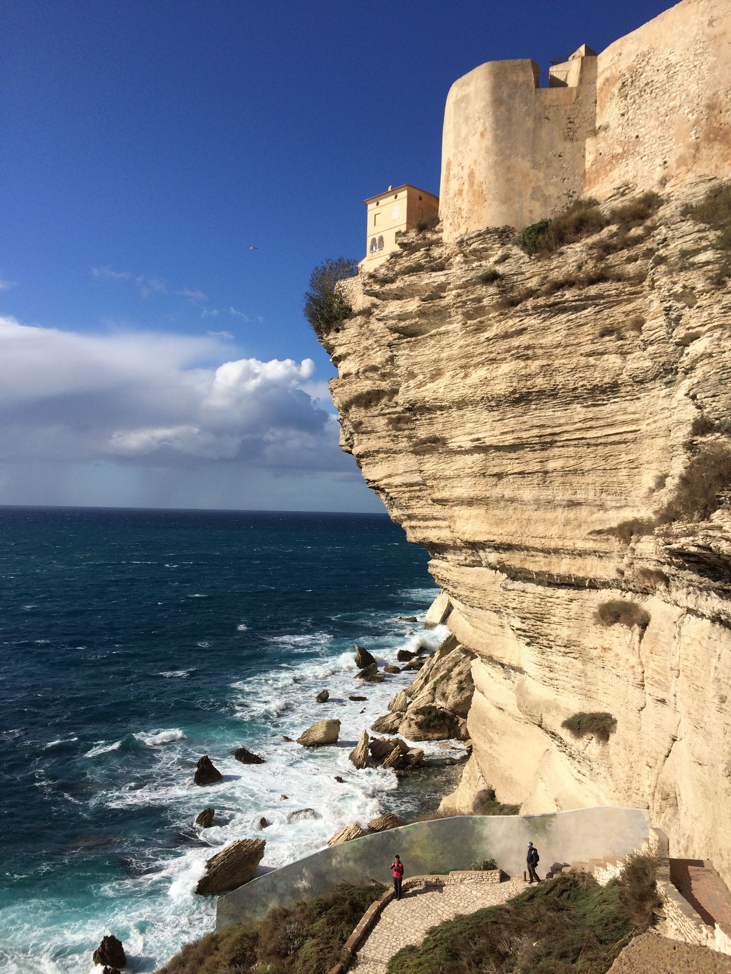 A coastal cliff with a castle-like structure on top, overlooking the sea.