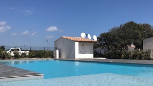 A swimming pool with a white building in the background. - Mini villa the top of bonifacio with heated pool (Bonifacio)