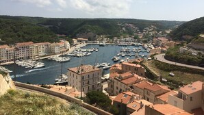 A coastal town with a marina filled with boats, surrounded by buildings with red-tiled roofs. - Mini villa the top of bonifacio with heated pool (Bonifacio)