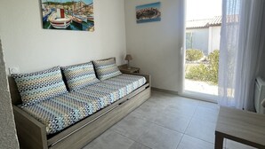 A modern room with a sofa bed, a dining table, and two paintings on the walls. - Mini villa the top of bonifacio with heated pool (Bonifacio)