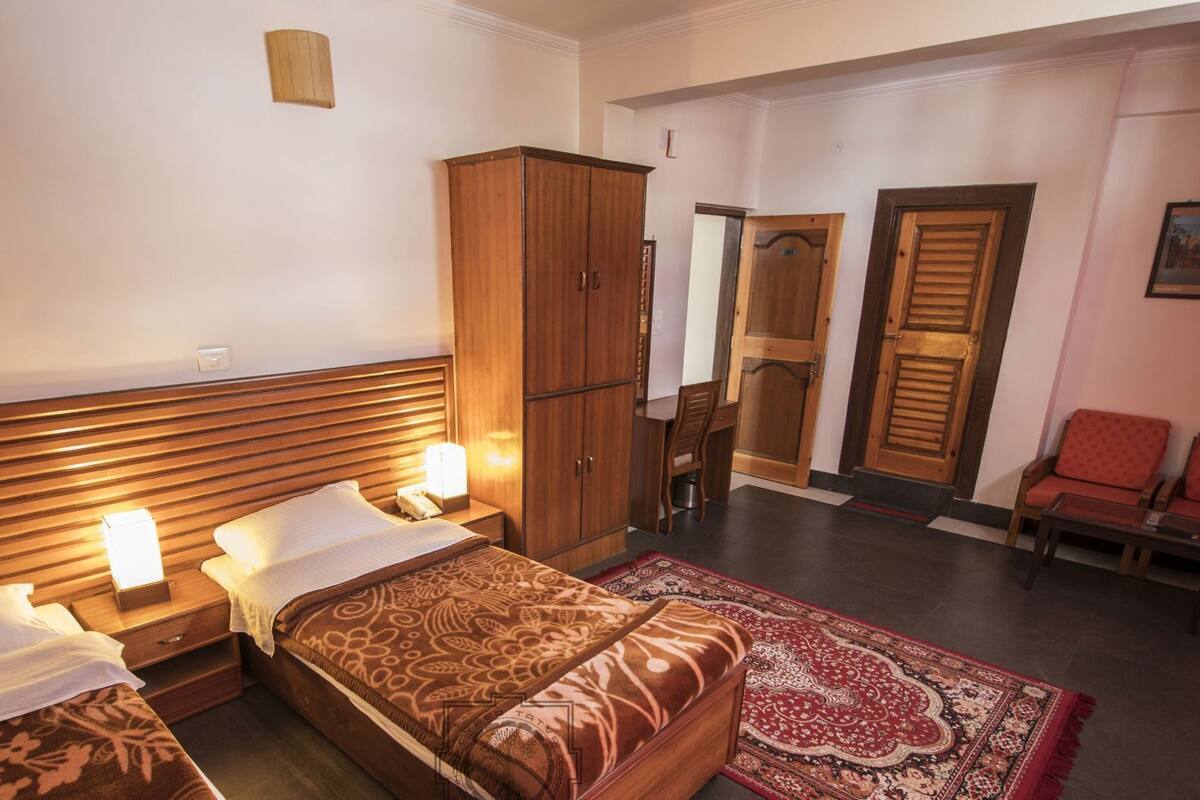 Camera d'albergo con un letto, comodini, un armadio, un angolo salotto con sedie e una porta che dà su un'altra stanza.