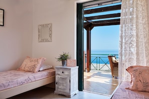 Relax in this serene retreat with a single bed, nightstand, and balcony offering a view of the sea.