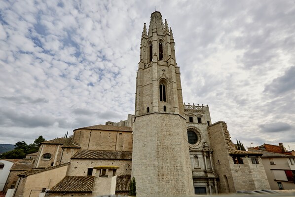 A historic church with a tall bell tower, a large circular window, and a fortified wall.