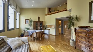 A spacious living room with a wooden floor, a dining area with a table and chairs, a sofa, and a wooden cabinet. - Amazing duplex near the cathedral in the heart to Girona (Gerona)