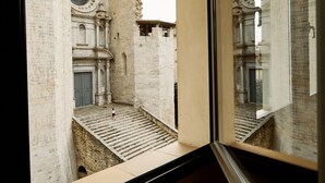 A room with a large window overlooking a historic building with arched windows and a staircase leading to a door. - Amazing duplex near the cathedral in the heart to Girona (Gerona)