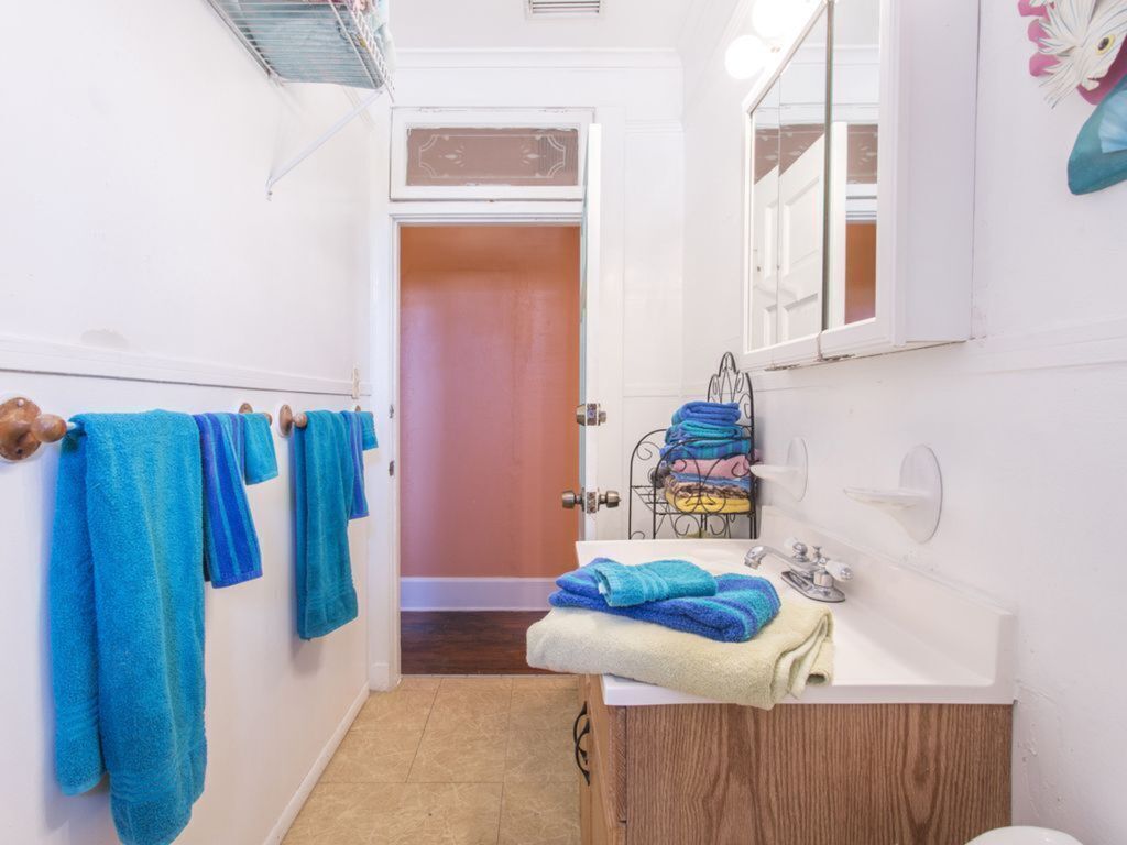 A bathroom with a white sink, a mirror, and a towel rack with blue towels.