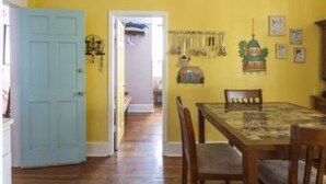 Un coin repas avec une table et des chaises en bois, un mur jaune et une porte bleue.