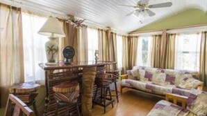 Un salon confortable avec un canapé, des fauteuils, une table basse et un ventilateur de plafond.